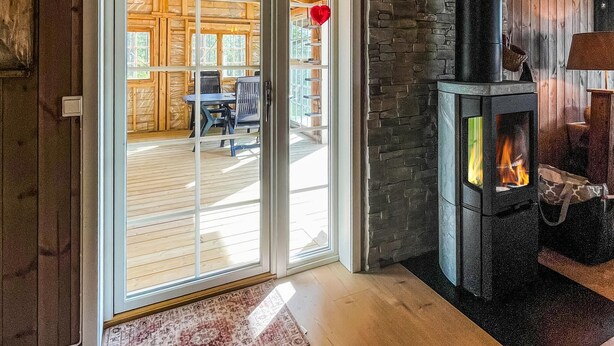 A wooden interior with a fireplace, a glass door leading to an outdoor area, and a rug on the floor. - Lovely home in Rendalen with WiFi (Rendalen)