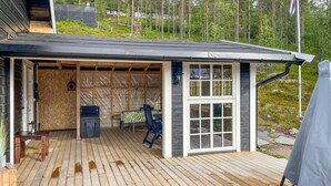 A wooden deck with a covered patio area, a table with chairs, and a small storage unit. - Lovely home in Rendalen with WiFi (Rendalen)