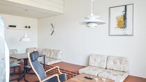 Uma sala de estar moderna com uma mesa de centro de madeira, dois sofás, uma mesa de jantar com cadeiras e uma luminária pendente.
