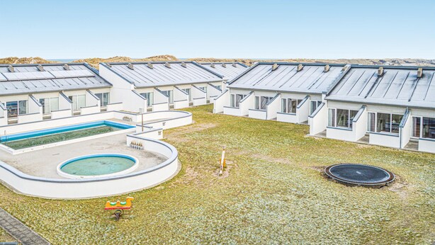Um complexo residencial moderno com várias casas, piscina e trampolim.