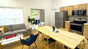 Una cocina moderna con comedor, que incluye una mesa de madera, sillas y un refrigerador.