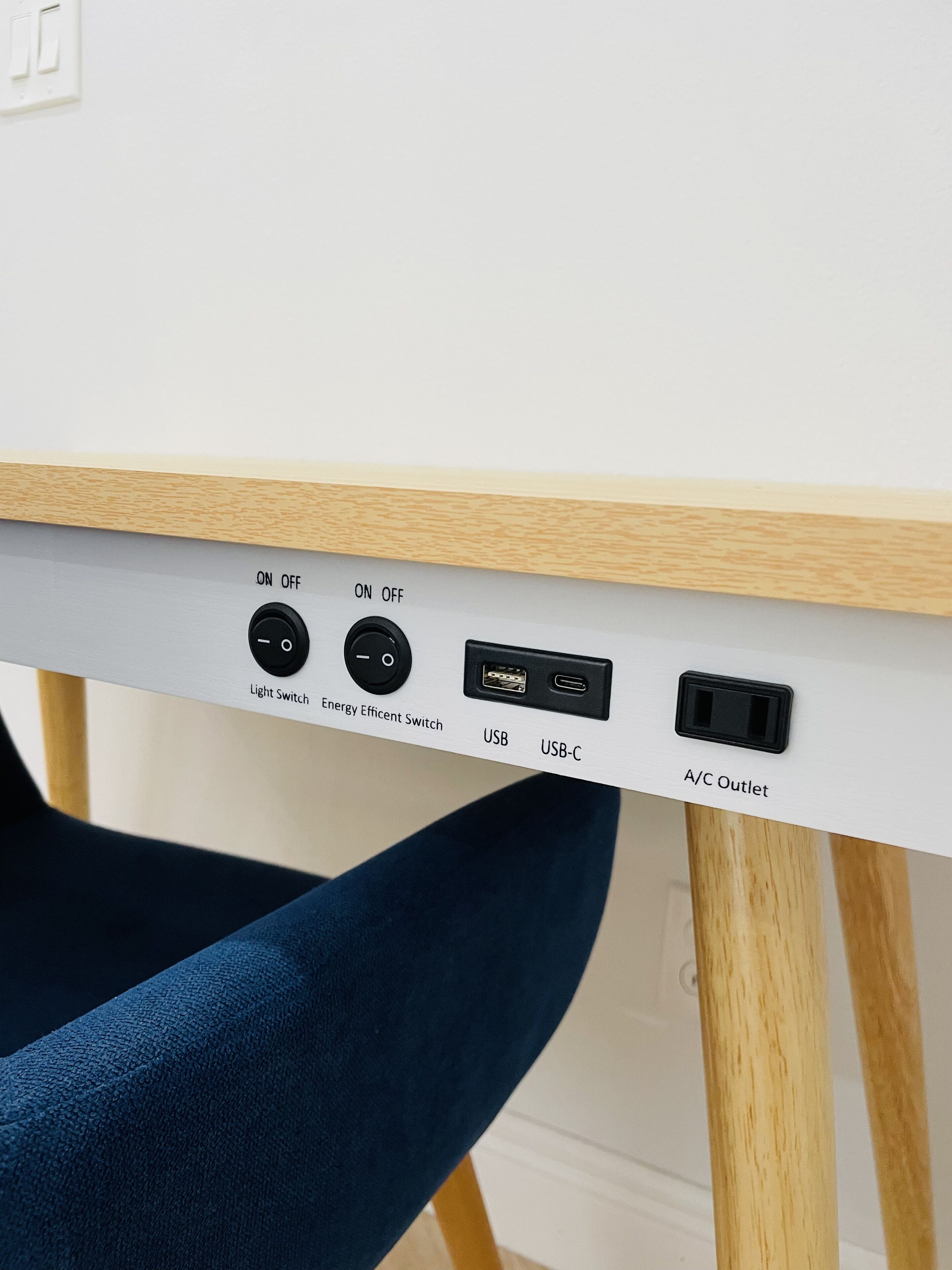 Una mesa con un interruptor de luz, un interruptor de bajo consumo, puertos USB y una toma de corriente de aire acondicionado.
