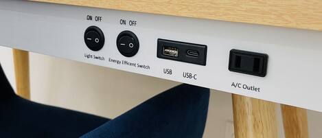 Una mesa con un interruptor de luz, un interruptor de bajo consumo, puertos USB y una toma de corriente de aire acondicionado.