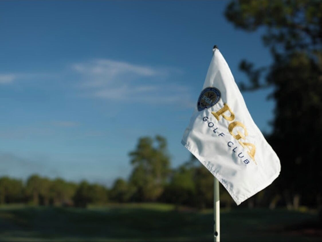 Un drapeau blanc sur lequel on peut lire « GOLF CLUB » et qui arbore un logo, fixé sur un mât.