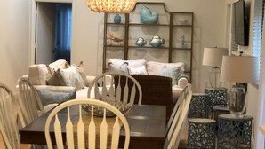 Un comedor con mesa y sillas de madera, una araña y objetos decorativos en estanterías.