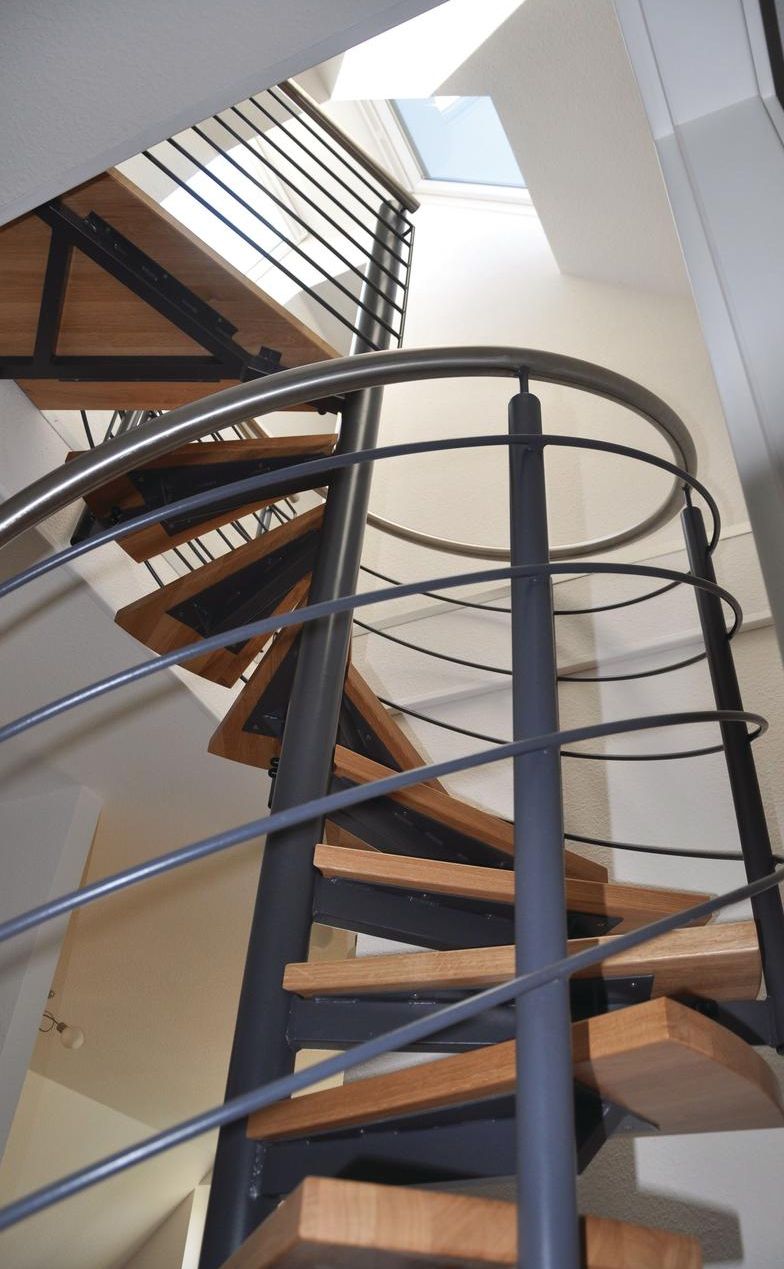 A spiral staircase with wooden steps and metal railings, leading to an upper floor.
