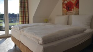 Een slaapkamer met een groot bed, een raam met gordijnen en een schilderij aan de muur.