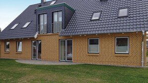 Een woonhuis met twee verdiepingen, een schuin dak, bakstenen gevel en meerdere ramen.