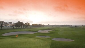 Een golfbaan met bunkers en een vlag.