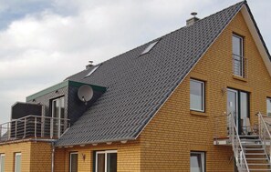 Ein zweistöckiges Haus mit geneigtem Dach, Satellitenschüssel und einem kleinen Balkon.
