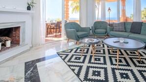 Amplia sala de estar con chimenea, dos sillones, un sofá y una mesa de centro.