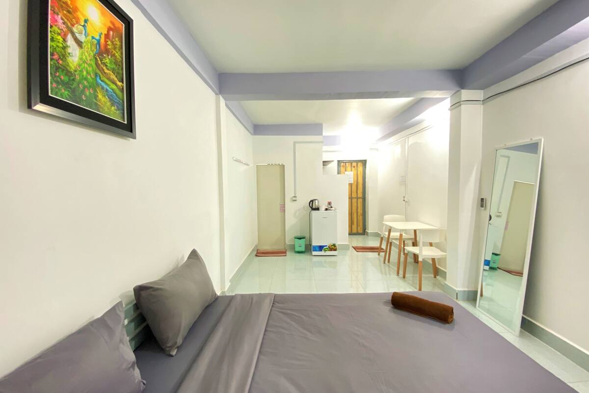 Une chambre d’hôtel avec un lit, un bureau, une chaise, un miroir et un tableau au mur.