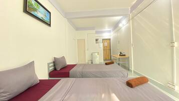 A hotel room with two beds, a small desk, a mirror, and a painting on the wall.
