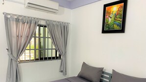A room with a bed, grey curtains, a painting, and a window with bars. - Sevenstars Hostel (Sihanoukville)