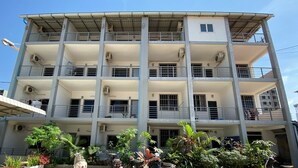 A multi-story building with balconies, air conditioning units, and a covered entrance. - Sevenstars Hostel (Sihanoukville)