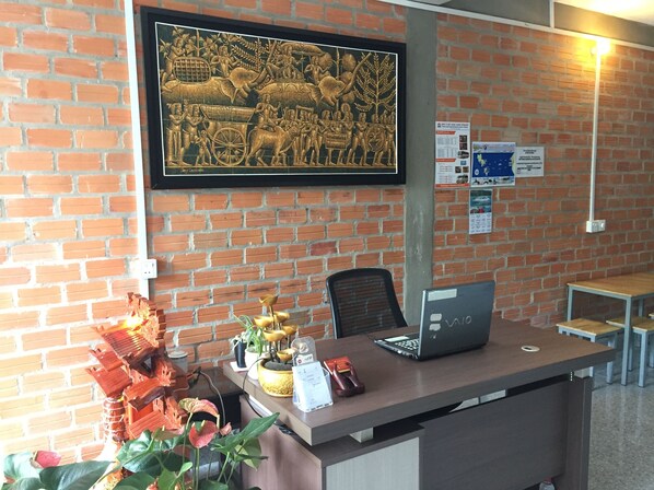 Uma receção com um laptop, um mural emoldurado e uma parede de tijolos.
