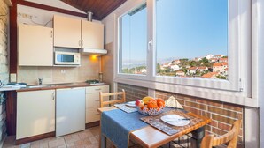 A kitchen with a view of a town, a dining table with fruit, and a window with a view. - Stunning apartment in Splitska (Splitska)
