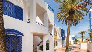A white building with blue accents, a palm tree, and a clear sky.