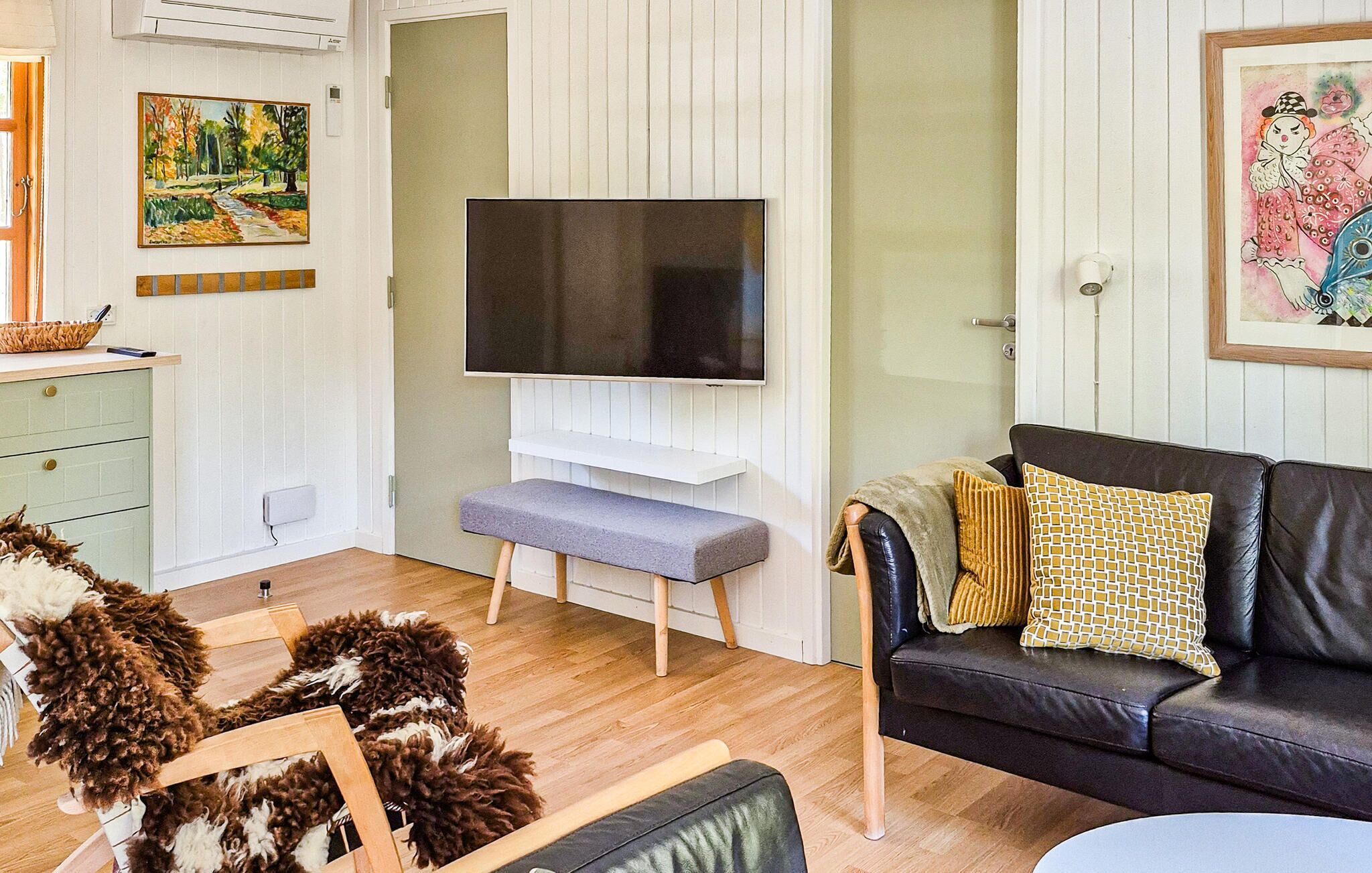 A living room with a TV, a sofa, a bench, and a dog.