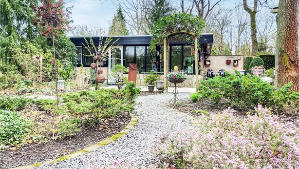Una casa moderna con un camino de jardín que lleva a una entrada con puerta de vidrio.