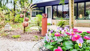 Un jardín con plantas en flor y un edificio moderno con grandes ventanales.