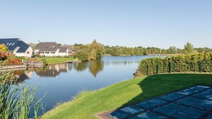 Uma propriedade tranquila à beira do lago, com gramado bem cuidado, um cais e uma fileira de casas com vista desobstruída para o lago.