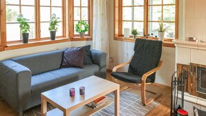 Una sala de estar acogedora con un sofá gris, una silla de madera, una mesita con dos tazas y una chimenea.