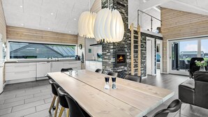 Een moderne keuken met een grote eettafel, zwarte stoelen en een open haard.