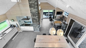 Een moderne keuken met een centraal eiland, een eethoek met een houten tafel en een open haard.