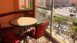 Un balcone con tavolo e sedie, vista su una strada con auto ed edifici.