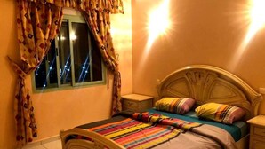 Una camera da letto con un letto di legno, una coperta a righe colorate e tende a motivi.