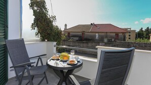 A balcony with a table set for two, featuring a plate of food, a glass of wine, and a banana. - Awesome apartment in Kastel Stari with house a panoramic view (Kastel Stari)