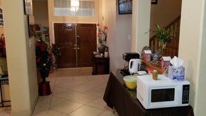 A kitchen area with a microwave, a coffee maker, and a small table with various items.