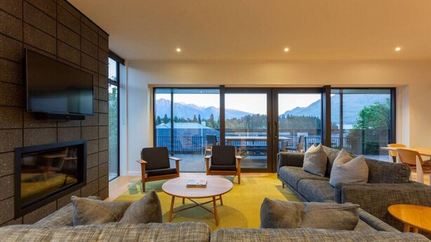 Un salón moderno con chimenea, ventanas amplias y vistas a las montañas.