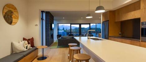 A modern kitchen with a large island, wooden cabinets, and a view of mountains.