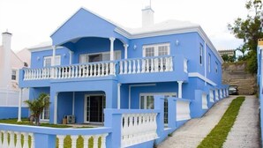A two-story house with a blue exterior and white trim, featuring a balcony with white balustrades. - Blue Diamond Apartments (Warwick Parish)
