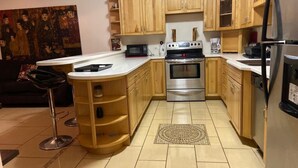 A kitchen with wooden cabinets, a stainless steel oven, a microwave, and a refrigerator. - Blue Diamond Apartments (Warwick Parish)