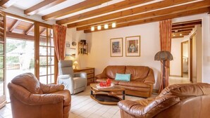 A living room with leather sofas, a coffee table, and a lamp. There are framed pictures on the wall and a window with curtains. - Marguerite by Interhome (Capbreton)