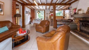 A spacious living area with leather sofas, a fireplace, and wooden beams on the ceiling. - Marguerite by Interhome (Capbreton)