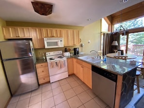 Compact kitchen with appliances and dining area, featuring a refrigerator, microwave, oven, and dishwasher.