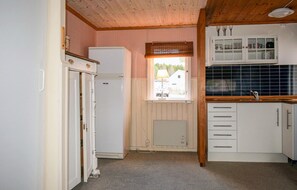 Enjoy cooking in this kitchen with a vintage vibe, featuring a refrigerator, cabinet with glass doors, and a window with a checkered blind.