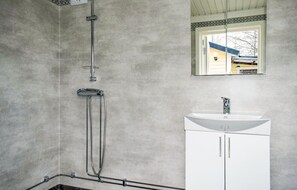 Bathroom features a shower with handheld showerhead and faucet, a sink with single faucet, and a mirror.