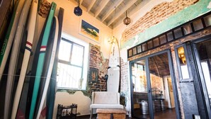A room with surfboards, a chair, and a wooden chest. - Mechudo Brewinn (La Paz)