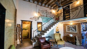 A loft-style living area with exposed brick walls, a staircase, and a ceiling fan. - Mechudo Brewinn (La Paz)