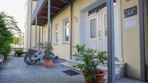 A building with a sign reading "Atlant" and a number "45" indicating a location or unit number. There are potted plants in front of the entrance, and a bicycle parked outside.