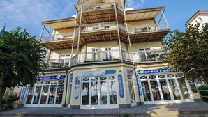 Un edificio de varios pisos con balcones, locales comerciales y cielo despejado.