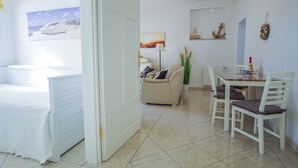 Una habitación con una cama, una mesa de comedor con sillas, un sofá y un cuadro de un barco en la pared.