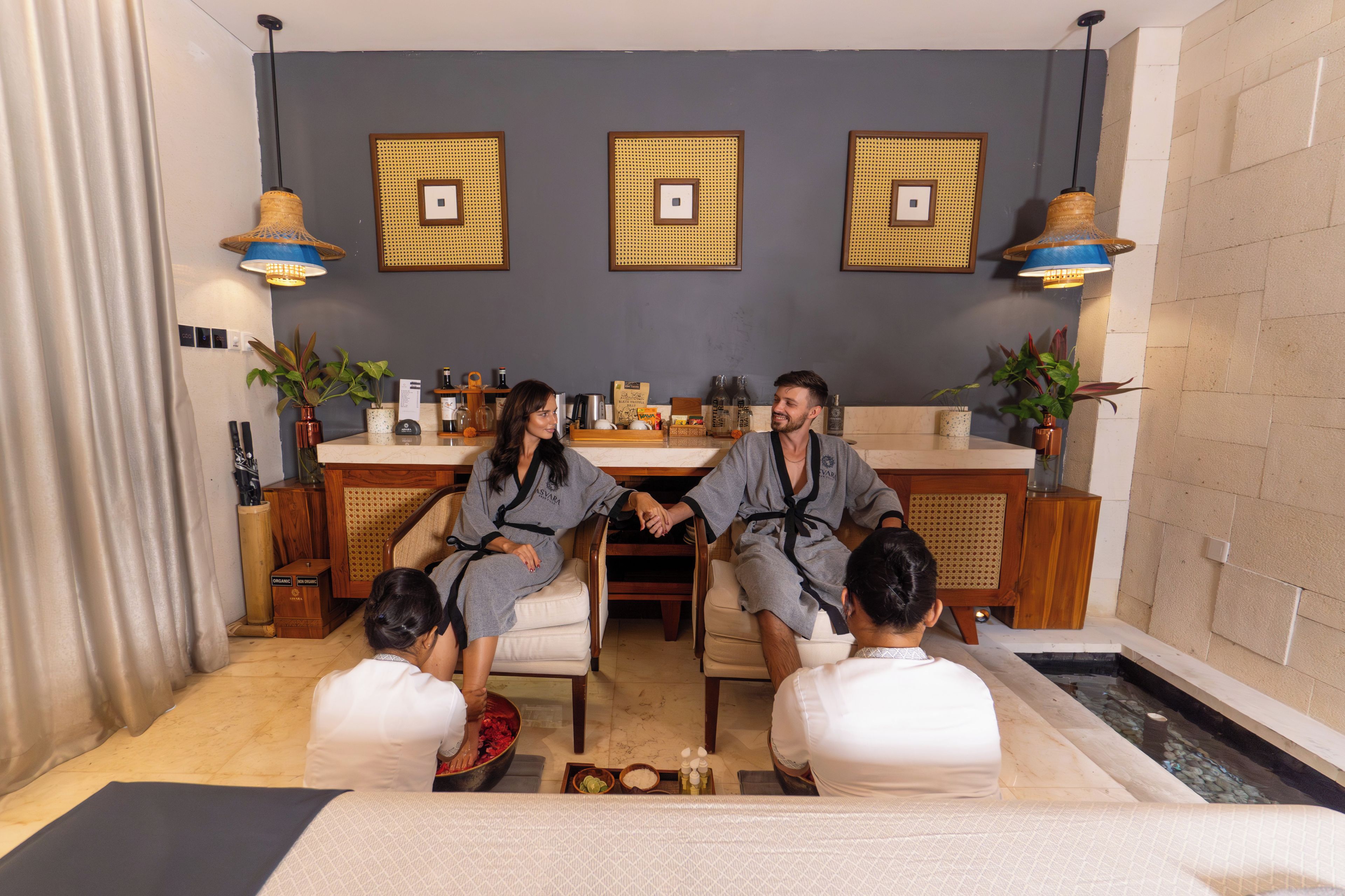 Una habitación con zona de estar, mostrador de recepción y pantalla mural.