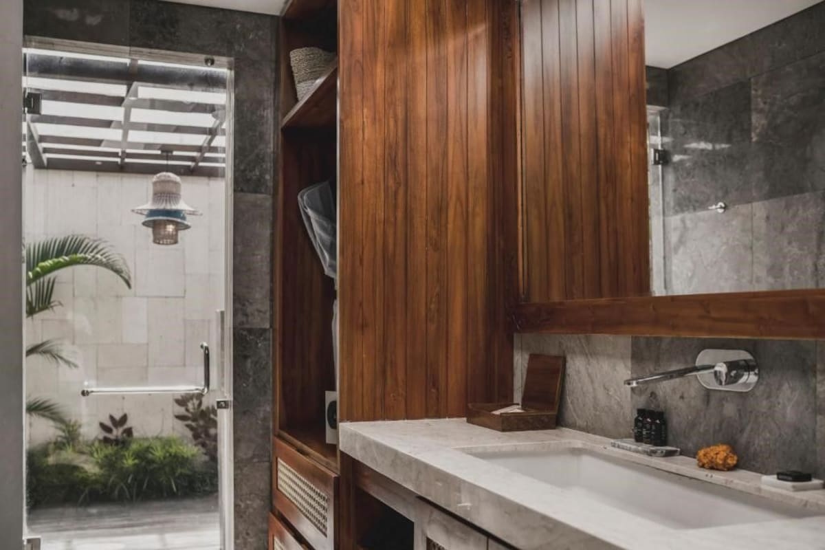 Une salle de bain avec un meuble-lavabo en bois, un lavabo en marbre et un espace douche.