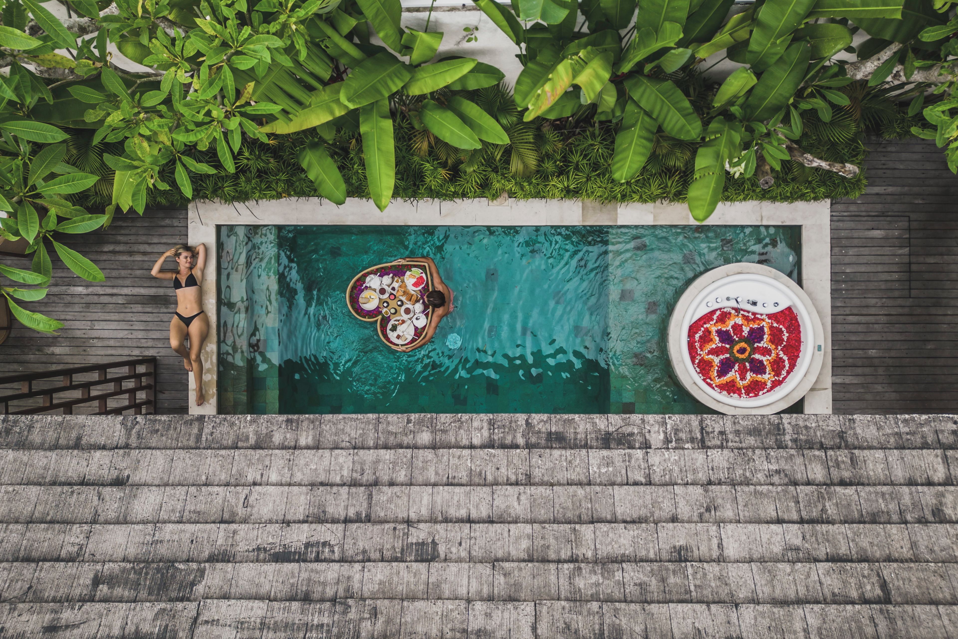 A swimming pool with a floating tray of food and a decorative plate on the edge.